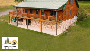 Une cabane en rondins avec un toit végétalisé, des fondations en pierre et une véranda dotée de balustrades en bois.