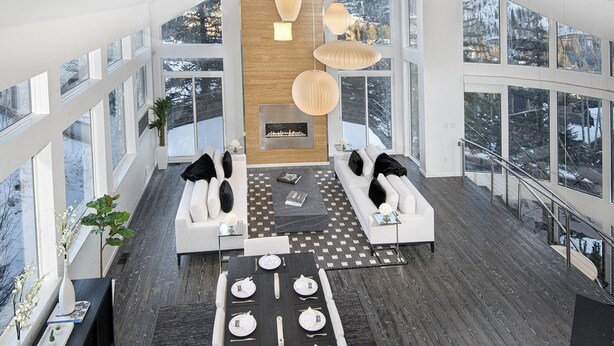 Un salon moderne doté d’une cheminée, de grandes fenêtres et d’un coin repas.