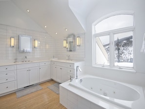 A modern bathroom with a large bathtub, two sinks, and a window with a snowy mountain view. - Apres Chalet (Vail)