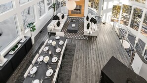 Un espace de restauration moderne, avec une longue table dressée pour un repas, entouré de grandes fenêtres offrant une vue sur un paysage enneigé.