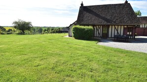 A traditional Tudor-style building with a thatched roof, a gravel driveway, and a well-maintained lawn.