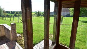 A room with a view of a grassy field and a brick wall.