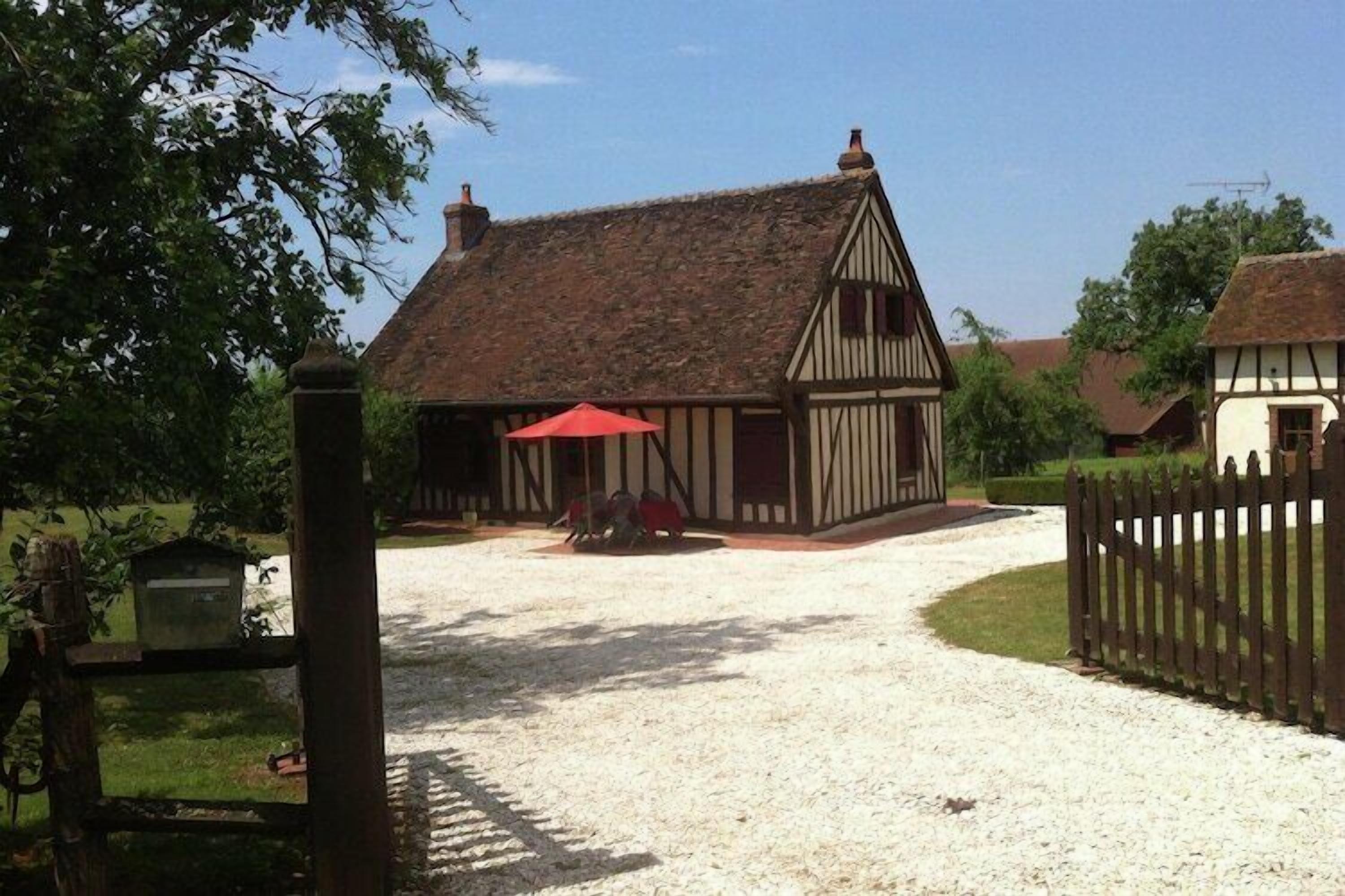 A traditional half-timbered building with a gravel driveway and a wooden fence.