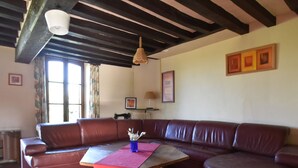 A living room with a brown leather sofa, a wooden coffee table, and a hanging light fixture.