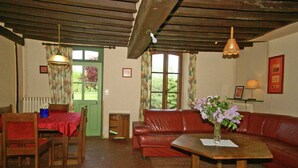 A cozy living room with a red leather sofa, a wooden coffee table, and a dining area with a table and chairs.
