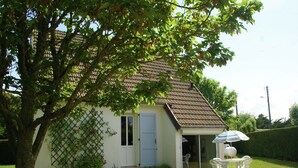 A house with a tiled roof, a door, and a small patio area with two chairs and a table. - Saint-Germain Beach Bliss (St. Germain-Sur-Ay)
