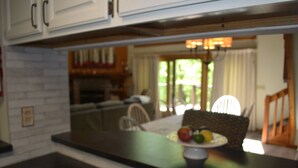 A kitchen with white cabinets, a black countertop, and a dining area with a table and chairs. - Condo < 1mi. from Mt. Snow / Free Shuttle (West Dover)