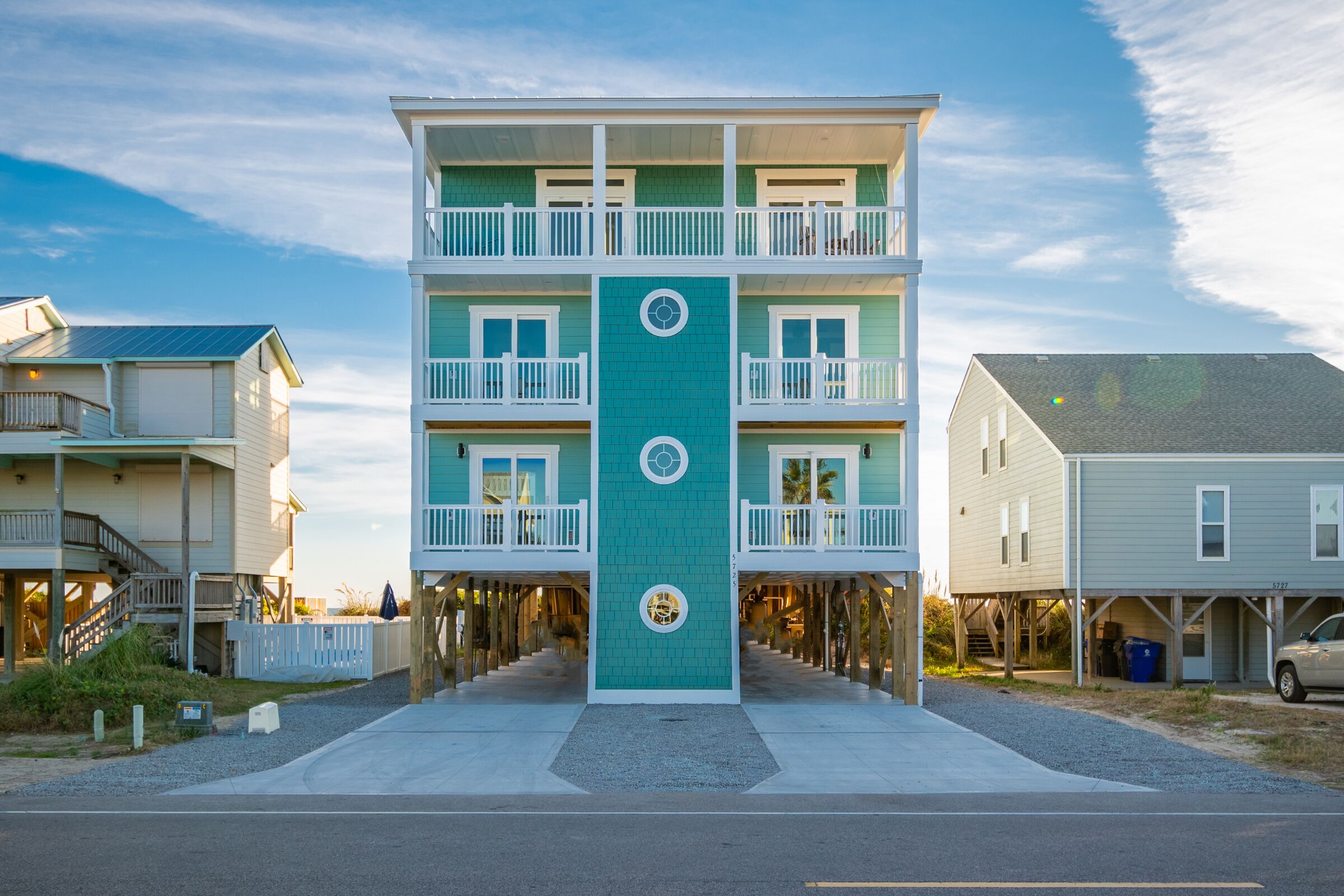 A multi-story building with a central vertical feature, balconies, and a covered walkway.