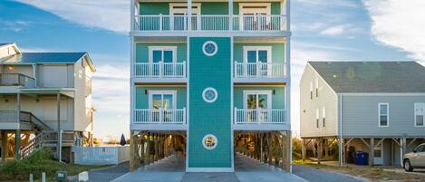 A multi-story building with a central vertical feature, balconies, and a covered walkway.