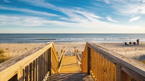 Un paseo marítimo de madera que conduce a una playa con cielo despejado.