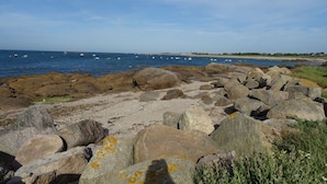 Uma linha costeira rochosa com grandes pedregulhos e uma vista clara do mar.