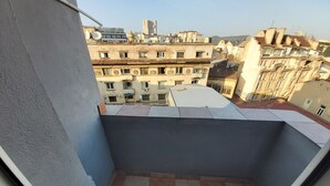 A small balcony with tiled flooring and a view of surrounding buildings.