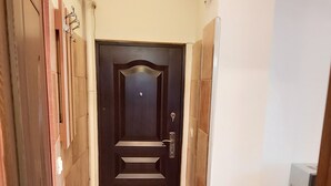 A hallway with a dark wooden door, tiled floor, and a white radiator.