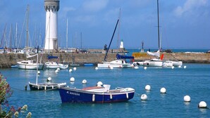 A harbor with boats, a lighthouse, and a stone wall.