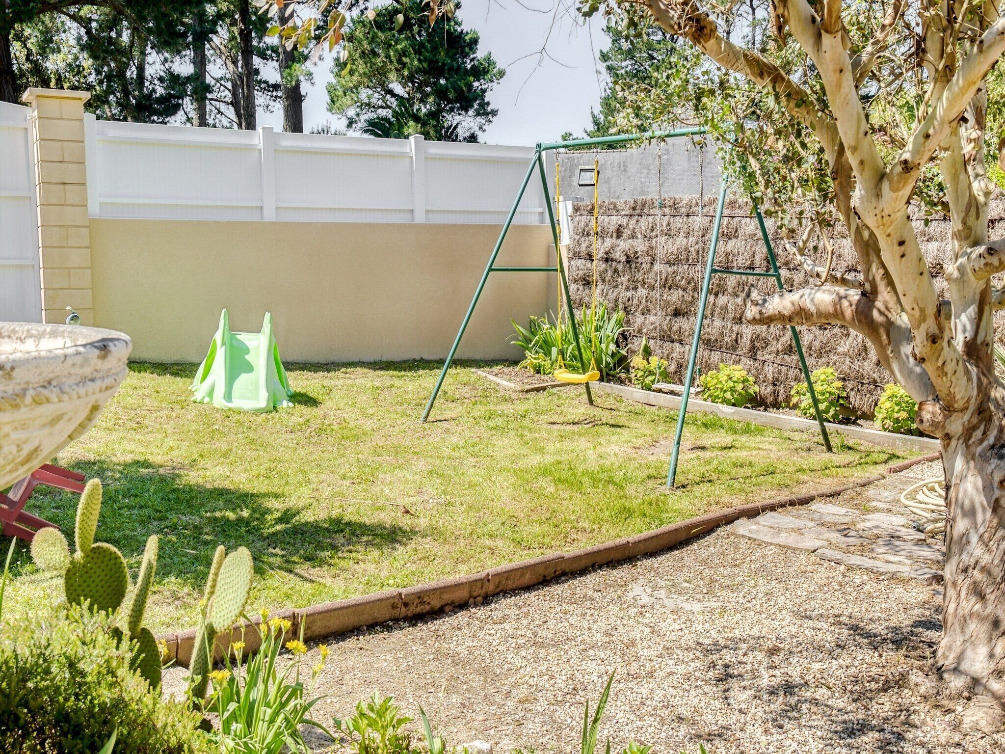 Un jardin avec une balançoire, un cactus et un parterre de fleurs.