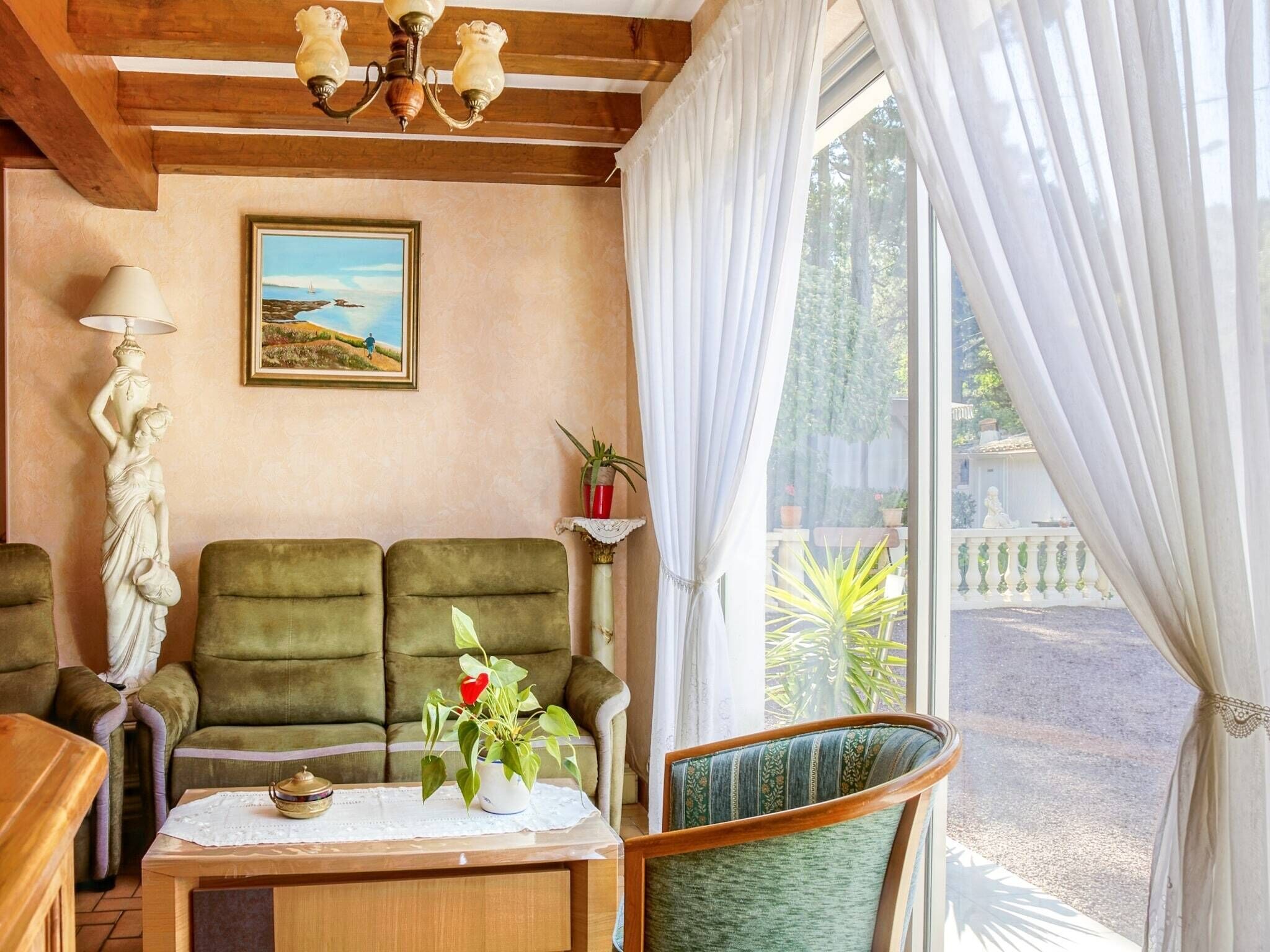 A cozy living room with a sofa, a chair, a table with a vase, and a painting on the wall.