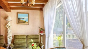 A cozy living room with a sofa, a chair, a table with a vase, and a painting on the wall.