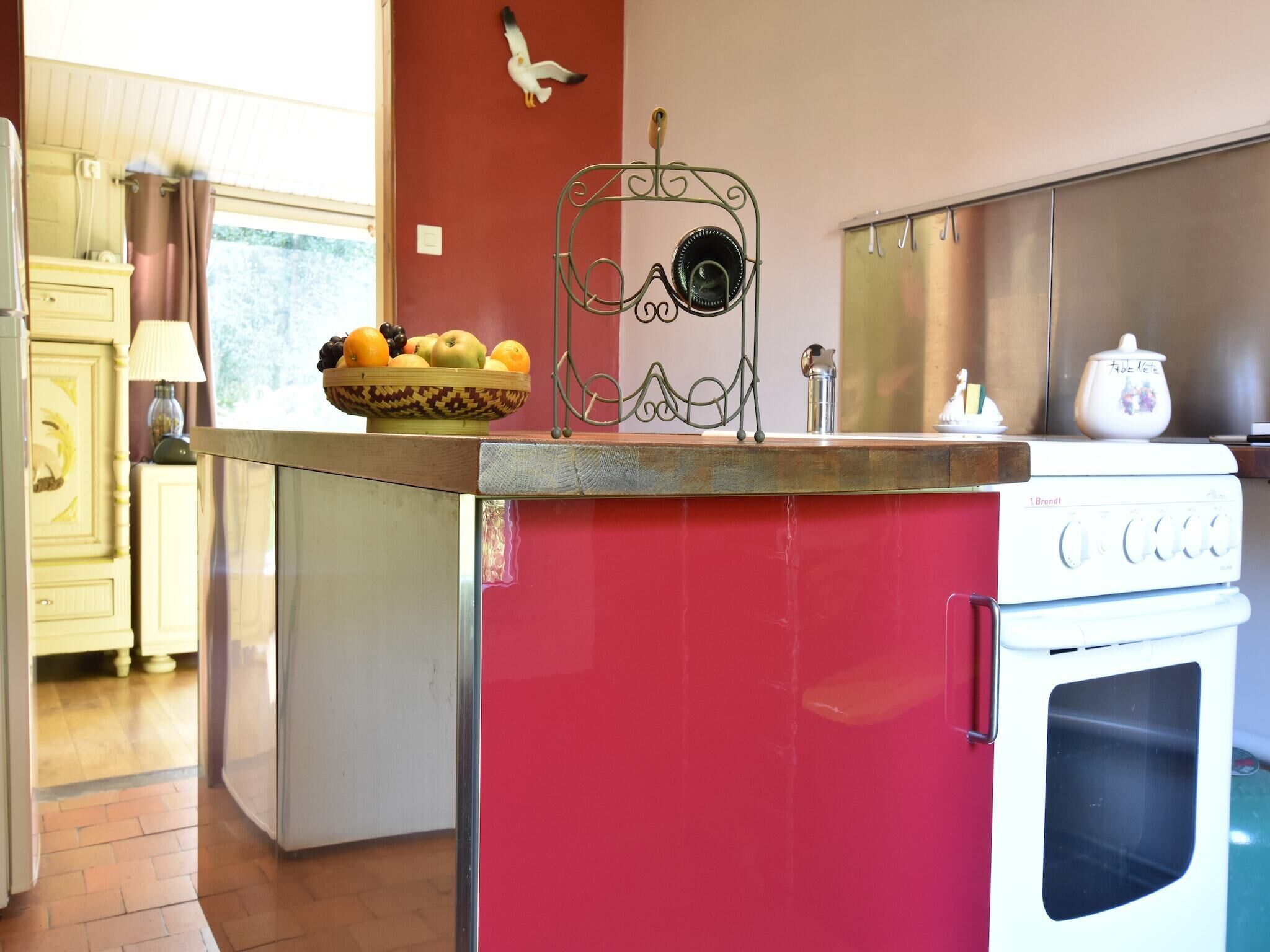 A kitchen with a red island, a white stove, and a fruit bowl on the counter.