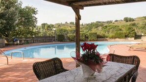 A poolside area with a table and chairs, a pool, and a view of the surrounding landscape. - La Villetta by Interhome (Riparbella)