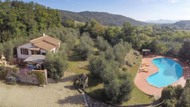 A villa with a swimming pool surrounded by lush greenery and hills in the background. - La Villetta by Interhome (Riparbella)