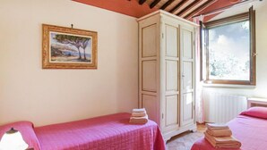 A room with two beds, a painting on the wall, and a window with a view of trees. - La Villetta by Interhome (Riparbella)
