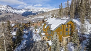 Un complejo turístico con cabañas de madera, rodeado de montañas y árboles cubiertos de nieve.