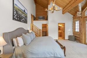 Une chambre à coucher avec un grand lit, un plafond en bois et un lustre.