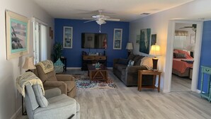 A living room with a sofa, armchair, and a television on a stand.