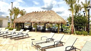 Un salon de plage doté de parasols en chaume, de chaises longues et de palmiers.