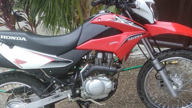 Una motocicletta Honda rossa e bianca parcheggiata su un fondo di ghiaia.