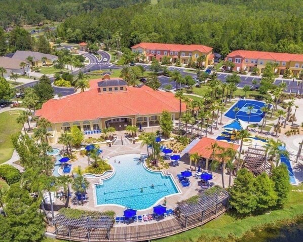 A resort with a central swimming pool, multiple buildings, and a landscaped area with palm trees. - Mickey’s Magic Retreat at Terra Verde Resort (Kissimmee)