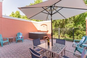 An outdoor patio with a table, chairs, and a large umbrella.