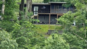 Ein modernes, zweistöckiges Haus, umgeben von dichtem Wald.
