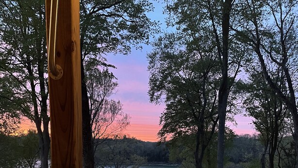 Ein Whirlpool mit Blick auf einen See und Bäume bei Sonnenuntergang.