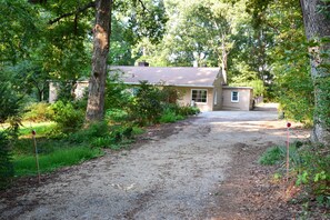 A house with a gravel driveway, surrounded by trees and greenery.