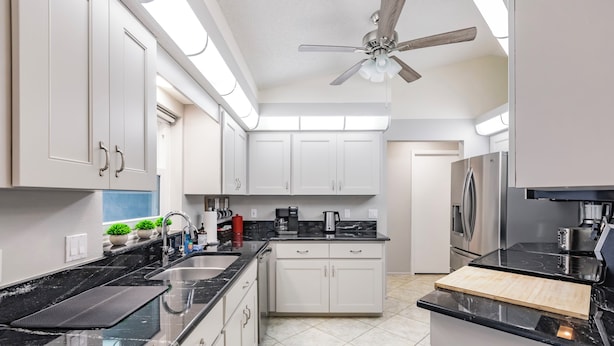 A modern kitchen with white cabinets, black countertops, and stainless steel appliances. - 8 min to Beach ★ 5TV★Air Hockey★ BBQ★ Bikes★Baby Gear ★Table Tennis ★Beach Gear (Venice)