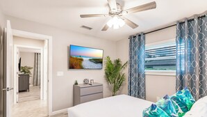 A bedroom with a bed, a ceiling fan, a TV, a nightstand, a plant, and a window with curtains. - 8 min to Beach ★ 5TV★Air Hockey★ BBQ★ Bikes★Baby Gear ★Table Tennis ★Beach Gear (Venice)