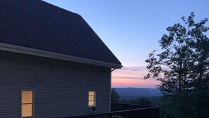 A house with a dark roof and two windows, a wooden deck, and a grassy yard. - Private House with Great View (Afton)