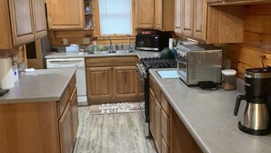 A kitchen with wooden cabinets, a stove, a microwave, and a coffee maker. - Private House with Great View (Afton)