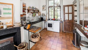 Une cuisine avec un sol carrelé, des placards en bois, une cuisinière et divers ustensiles de cuisine.