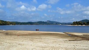 A beach with a boat on the shore, a sandy area, and distant hills. - Holiday Home in Limousin near Forest (La Veytisou)