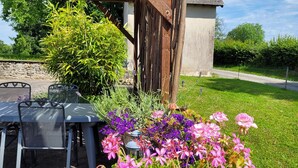 A patio with a table and chairs, surrounded by a variety of flowering plants. - Holiday Home in Limousin near Forest (La Veytisou)