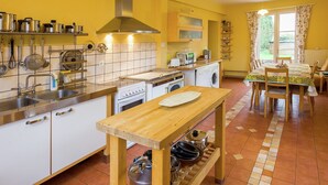 A compact kitchen with white cabinets, a wooden table, and a tiled floor.