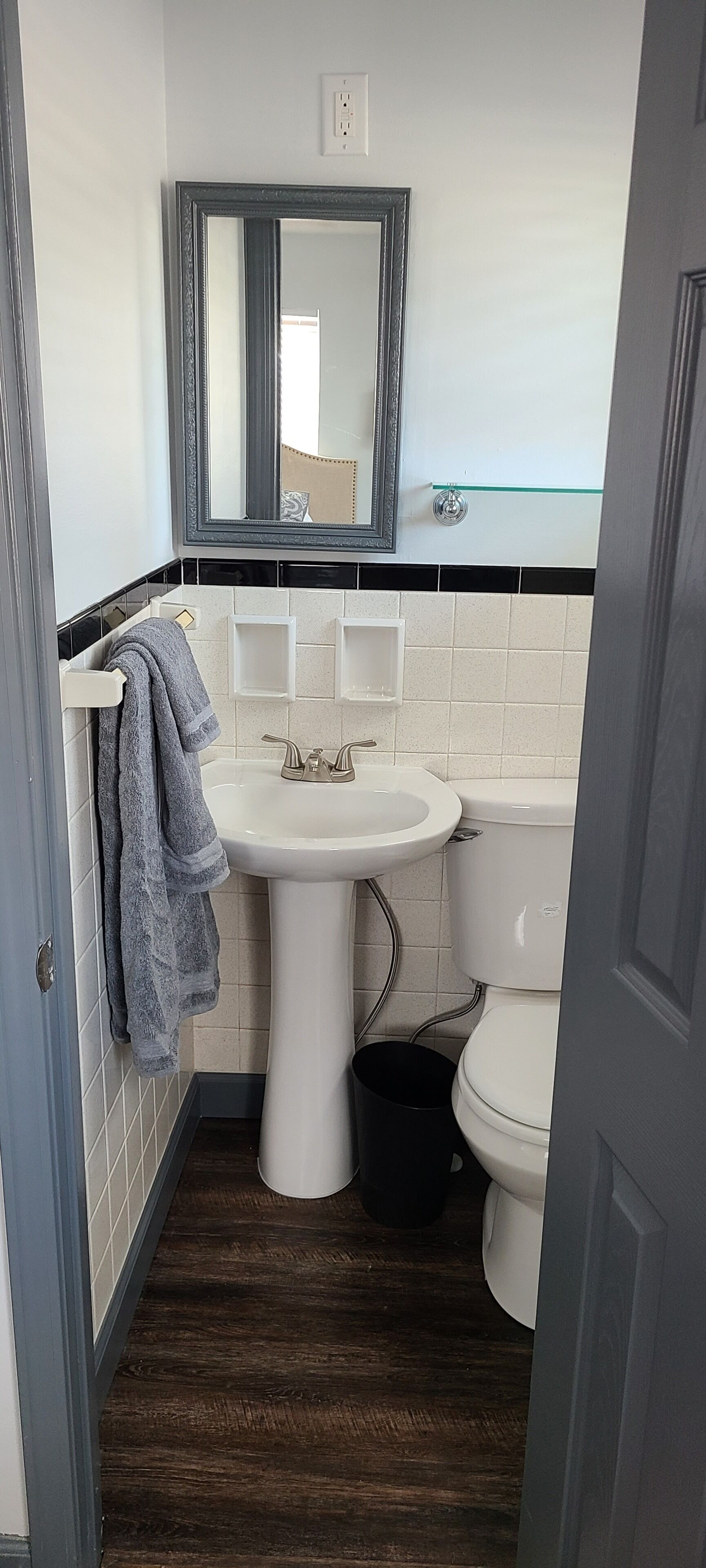A bathroom with a pedestal sink, a toilet, and a mirror above the sink.