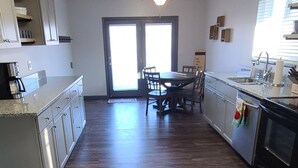 Una cocina amplia con suelo de madera, una zona de comedor y un ventanal corredero que da a un balcón.