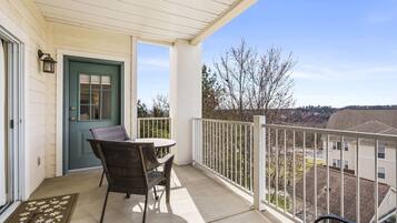 A balcony with a table and chairs, a door, and a view of the neighborhood.