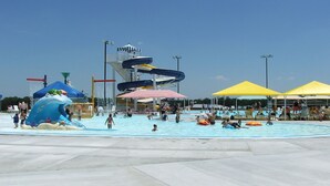 A water park with a large pool, slides, and umbrellas.