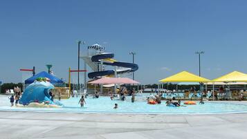 Un parque acuático con una piscina grande, toboganes y sombrillas.