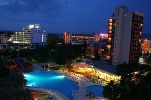 Un hotel con piscina, tobogán de agua y varias edificaciones con ventanas iluminadas.