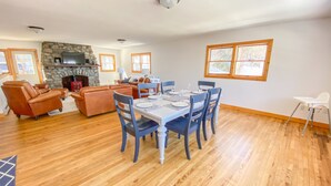 Un salón espacioso con chimenea, un comedor con mesa dispuesta para cuatro personas, y una zona de estar acogedora con sofás de cuero.